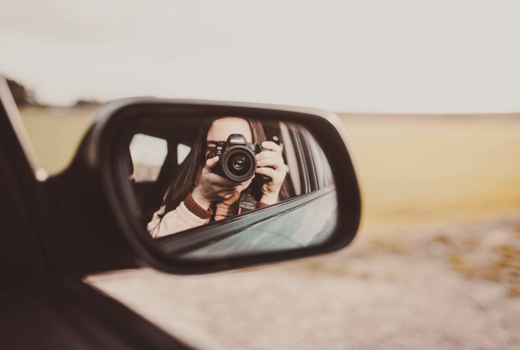 a person taking a picture of himself in a car mirror