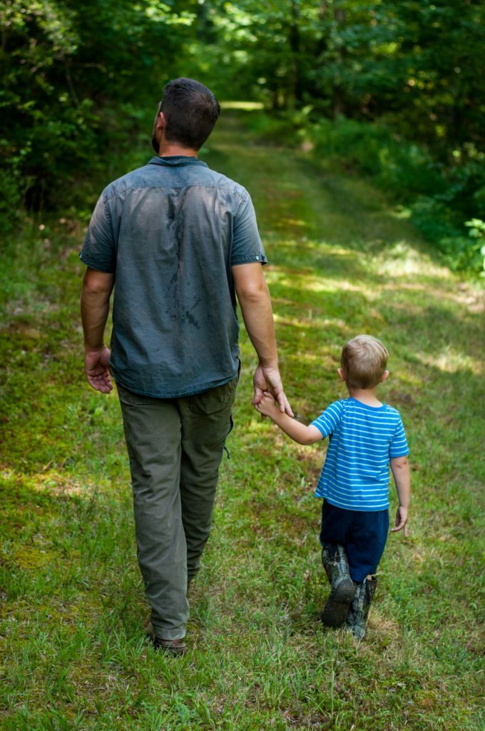 a man and a child walking in a grassy area
