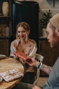 a man and a woman holding a pizza